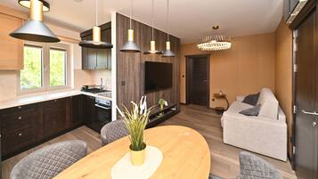 A modern kitchen with pendant lighting, a dining area with a wooden table, and a living room with a sofa.