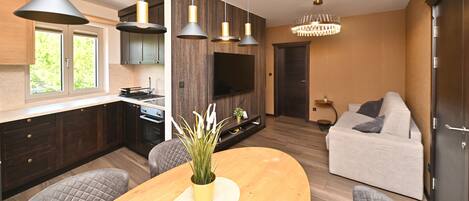 A modern kitchen with pendant lighting, a dining area with a wooden table, and a living room with a sofa.