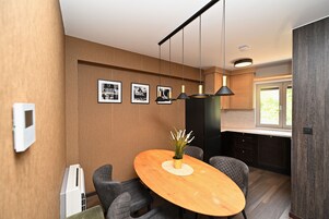 Una cocina moderna con una mesa de comedor de madera, luces colgantes e imágenes enmarcadas en la pared.
