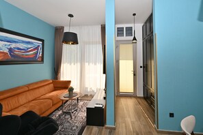 A modern living room with a sofa, a small table, a potted plant, and a painting on the wall. - Casa Nuova (Kotor)