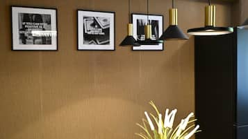 Un salón de conferencias con una mesa de madera, una planta en maceta, carteles motivacionales enmarcados e iluminación colgante.