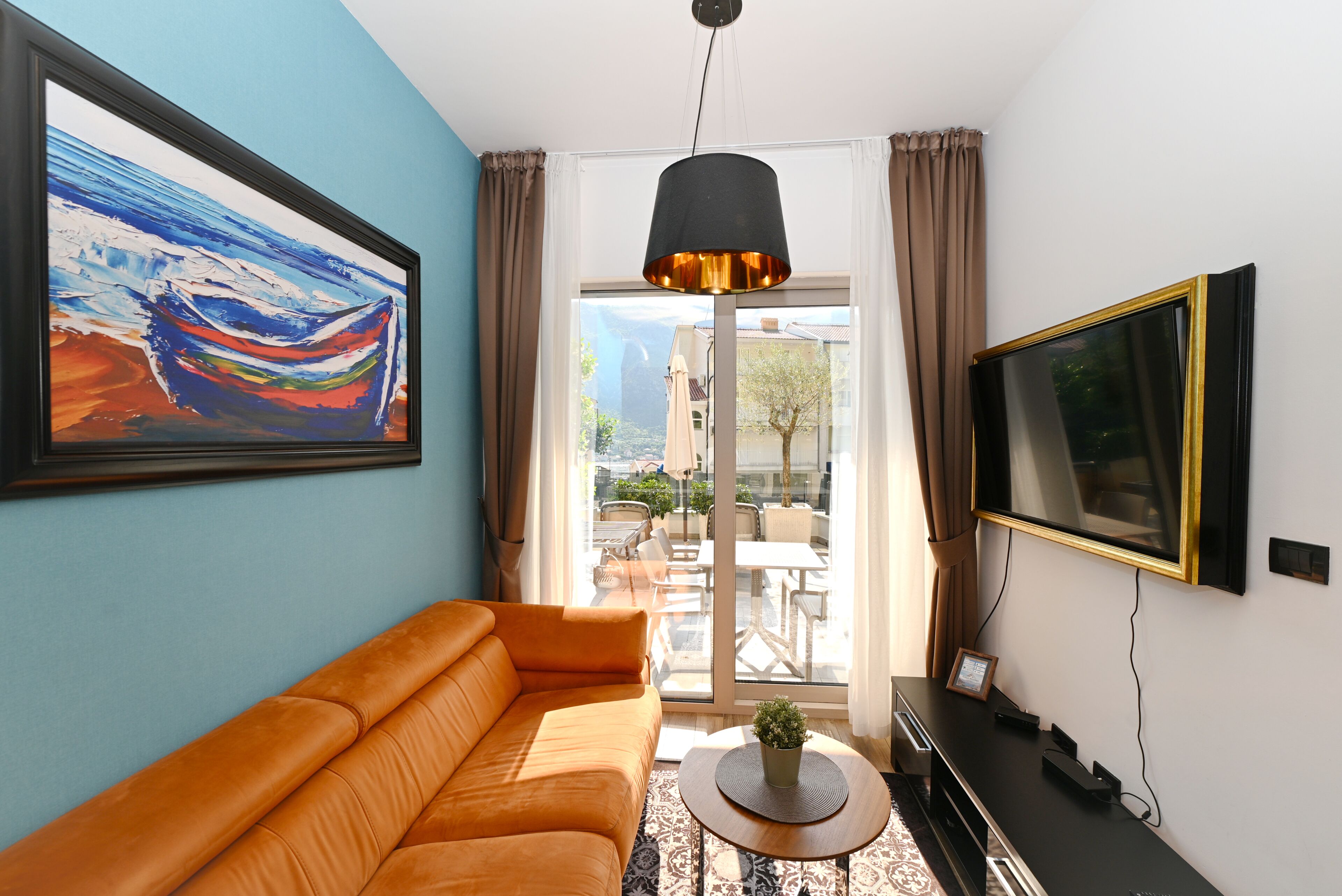 Una sala de estar con un sofá, una mesa de centro, un televisor y un cuadro en la pared.