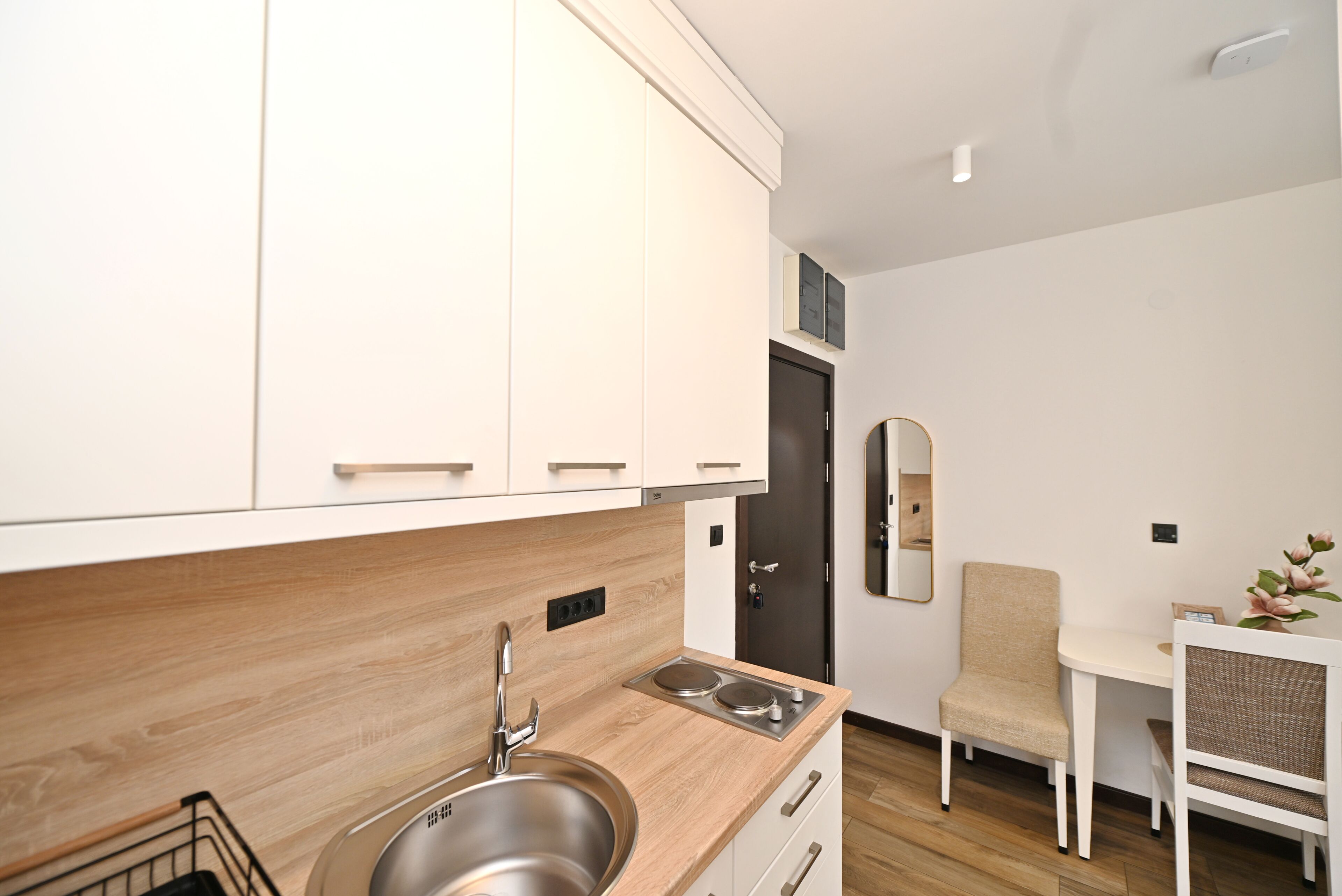 A modern kitchen with white cabinets, a stainless steel sink, and a wooden countertop.