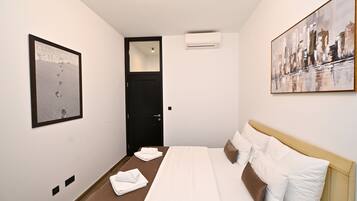Ein Hotelzimmer mit einem Bett, einer Tür, einer Klimaanlage und zwei Kunstwerken an den Wänden.