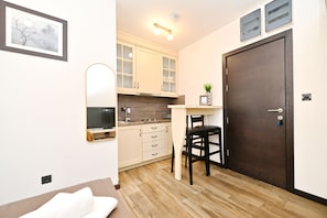 Una cocina compacta con armarios de madera, una puerta oscura y un pequeño comedor con una silla.