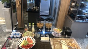 A buffet setup with various food items, including fruits, salads, and beverages.