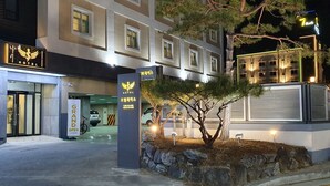 Ingresso di un hotel con un cartello che indica 'Grand Open' e un cartello '7 Plus' sopra.