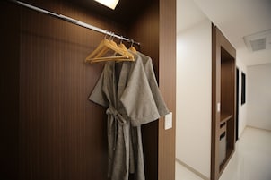 A hallway with wooden paneling, a robe hanging on a rack, and a mirror on the wall.