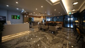 Hall d'albergo con reception, area salotto e bar.