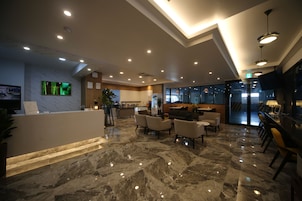 Vestíbulo de hotel con mostrador de recepción, zona de estar y bar.