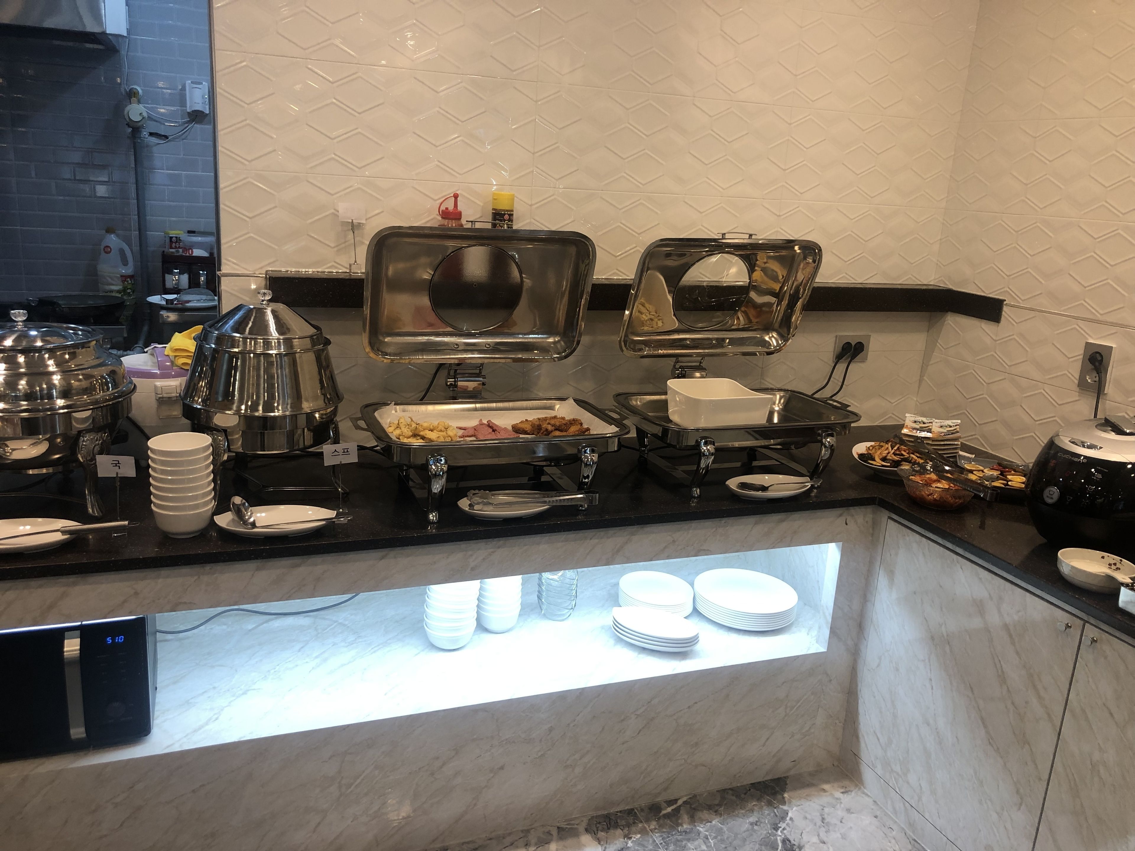 A buffet setup with various food items and serving utensils.