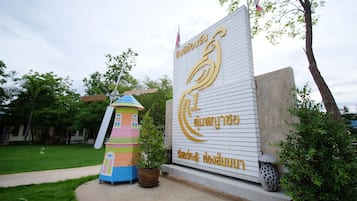 A building with a large sign featuring Thai script and a windmill-like structure.