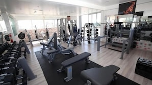 Un gimnasio moderno con diversos equipos de ejercicio, como mancuernas, bancos y máquinas de pesas.