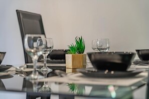A dining table with a laptop, a small plant, and a few wine glasses. - Thomas Apartments (Ayia Napa)