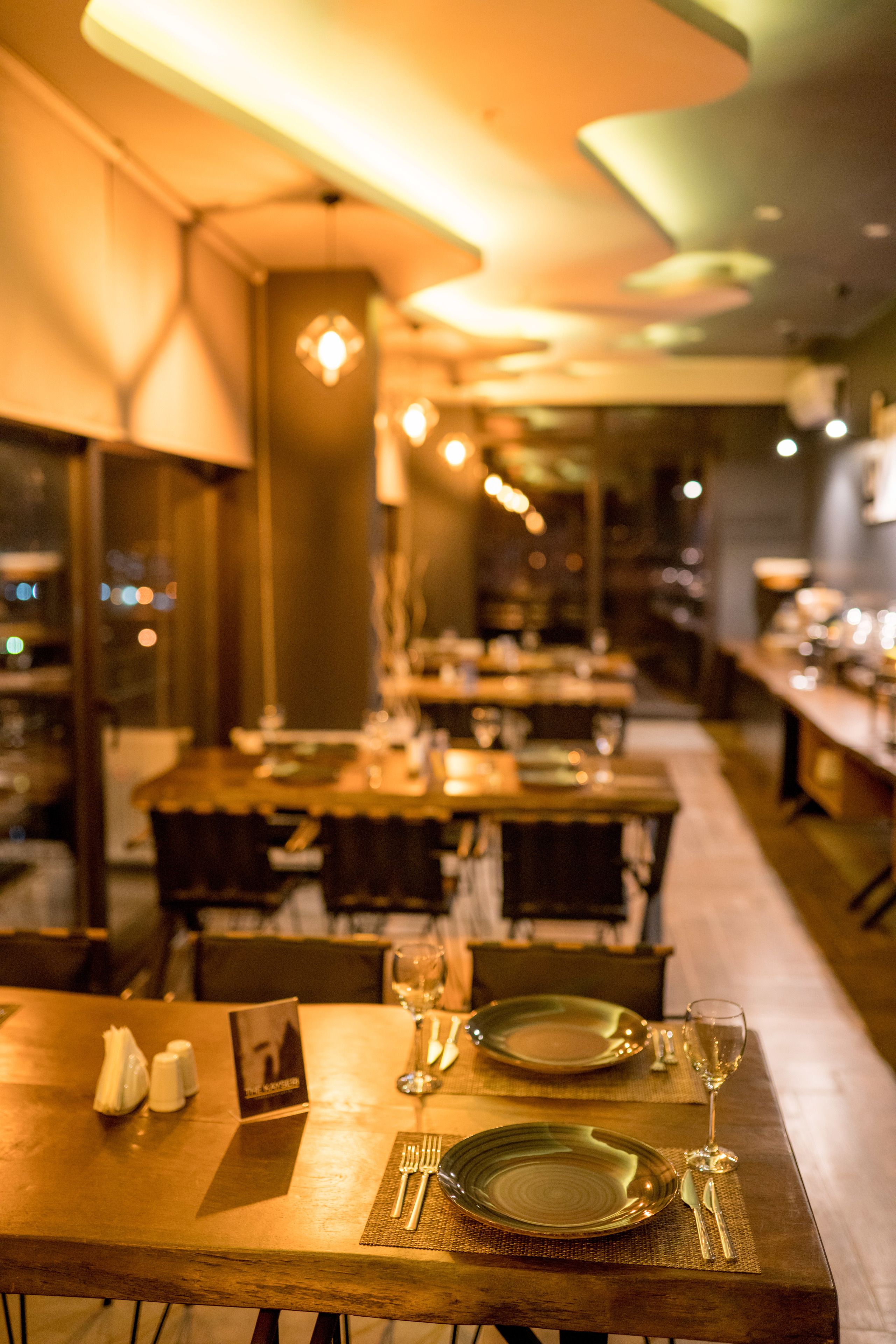 A restaurant with tables set for dining, featuring a warm ambiance and modern decor.