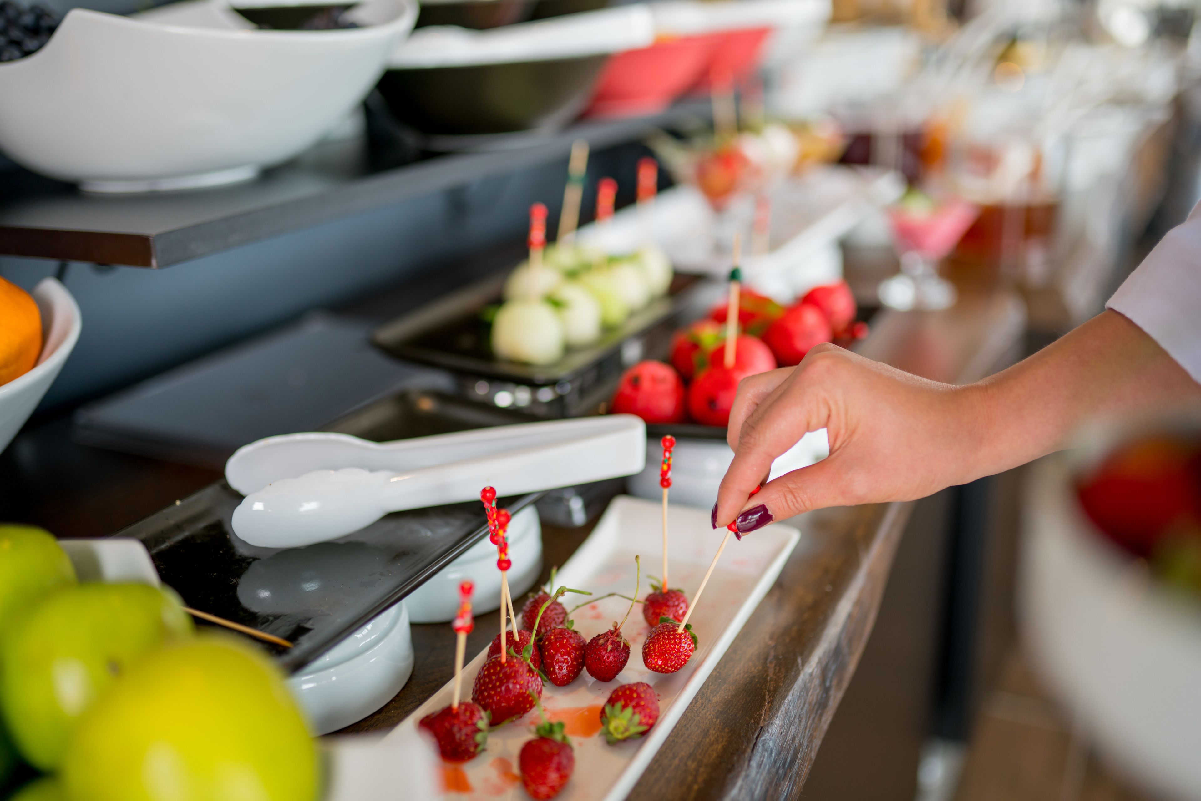 A buffet with various food items, including strawberries on skewers and other dishes.