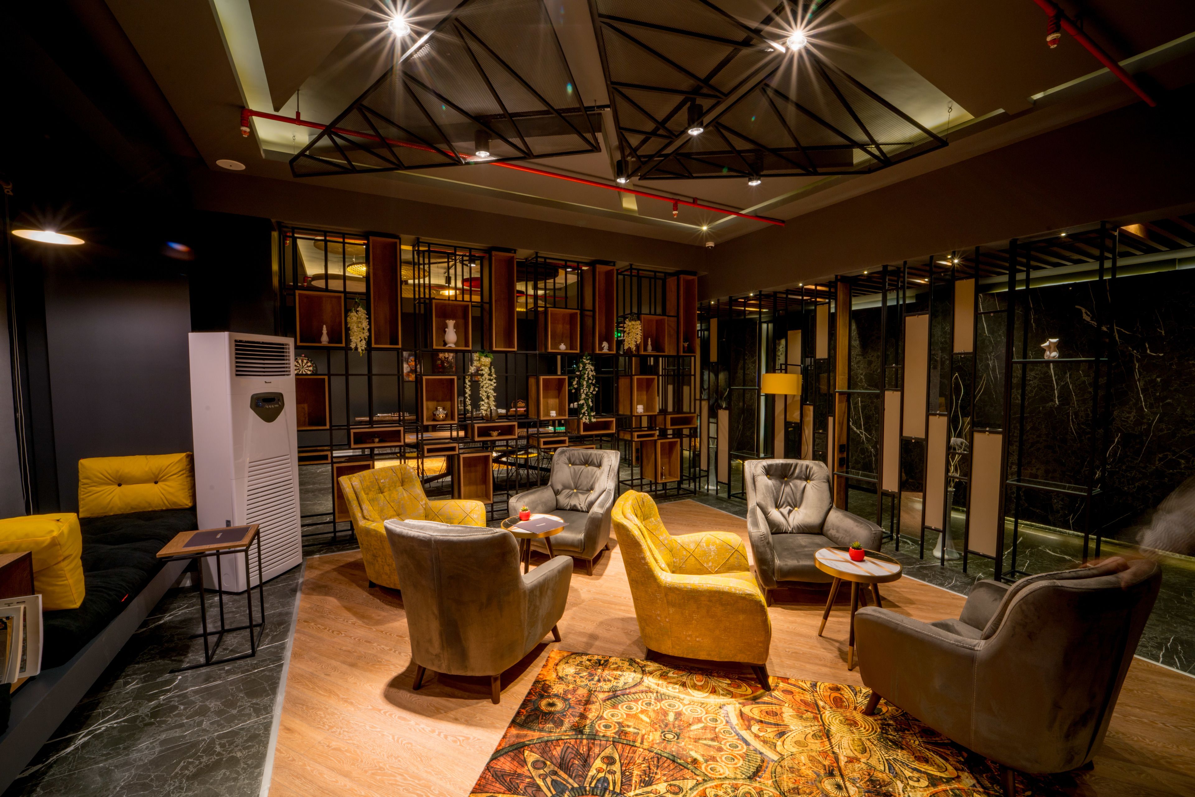 A modern lounge area with leather armchairs, a patterned rug, and a glass wall with a view.