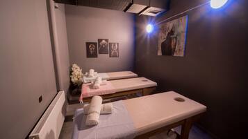 Um salão de spa com três mesas de tratamento, um radiador e obras de arte nas paredes.