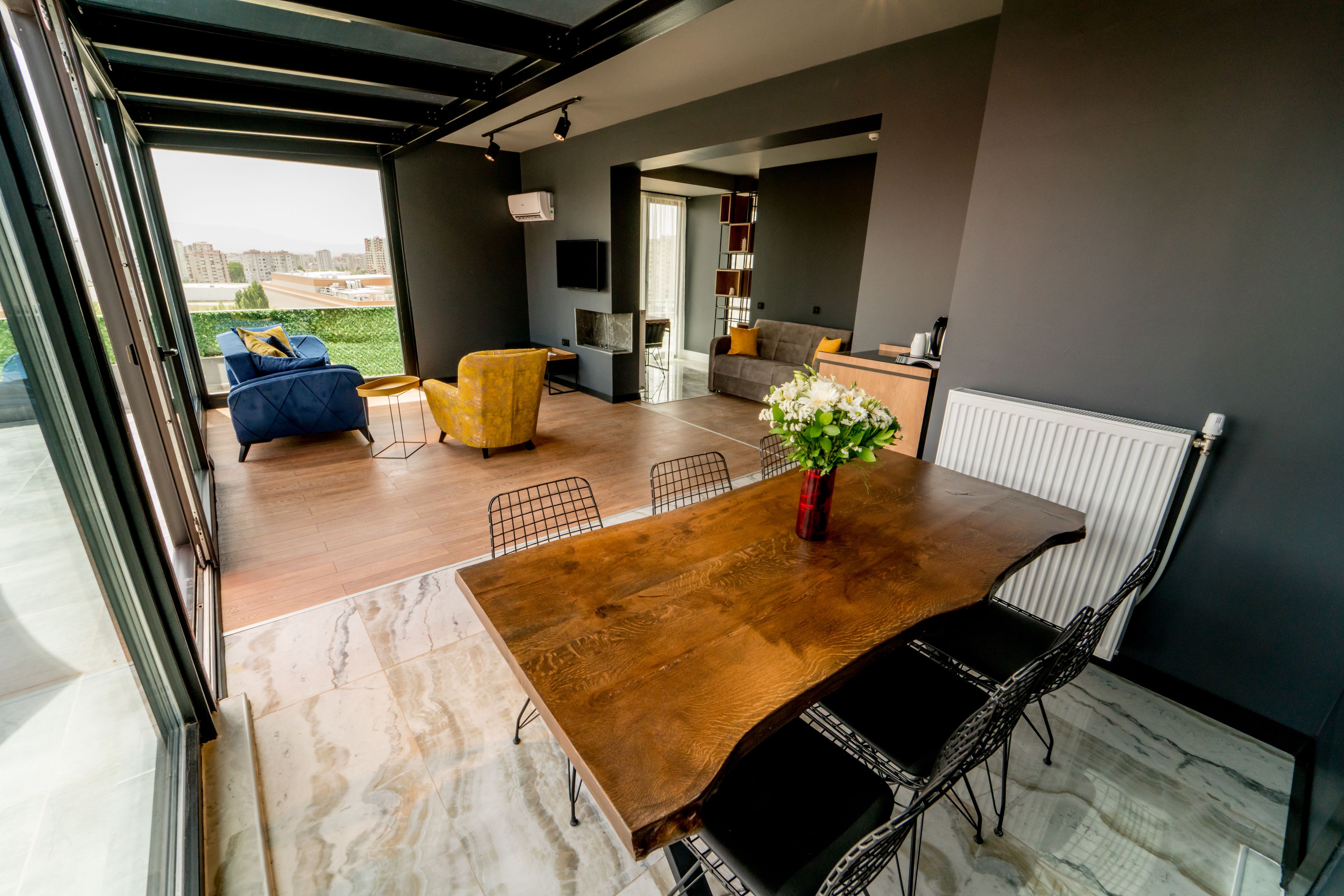Un espacio habitable moderno con una mesa de comedor de madera, sillas negras, un sofá y un sillón amarillo.