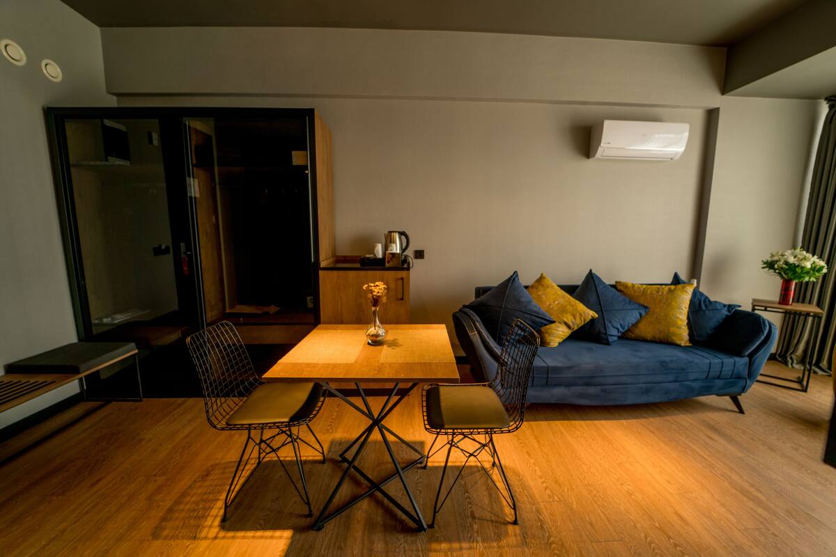 Ein modernes Wohnzimmer mit einem Holzesstisch, zwei Stühlen, einer Couch mit Kissen und einem Couchtisch.
