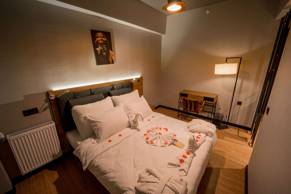 Ein Hotelzimmer mit Bett, Nachttisch, Stuhl, Lampe und Heizkörper.