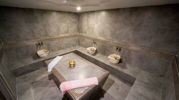 Bathroom features a large bathtub, two toilets, and grey tile walls and floor.
