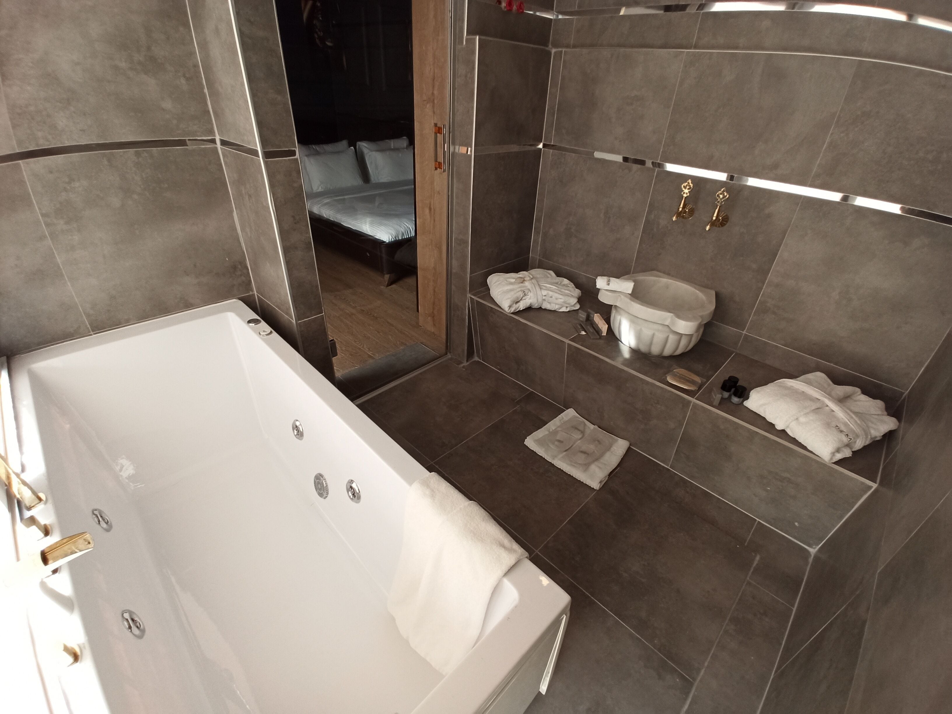 A modern bathroom with a large bathtub, a shower area, and a vanity with a sink and storage.