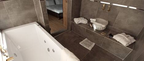 A modern bathroom with a large bathtub, a shower area, and a vanity with a sink and storage.