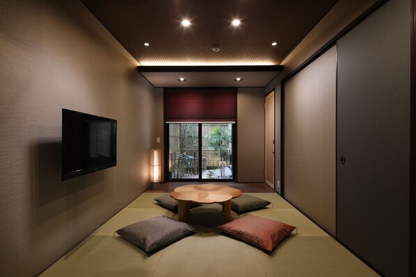Una habitación tradicional japonesa con suelo de tatami, una mesa de madera baja y cojines.