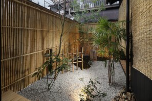A bamboo fence, a wooden deck, and a gravel area with plants.