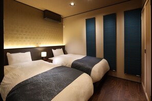 A hotel room with two beds, a headboard, a nightstand, and a wall-mounted air conditioner.