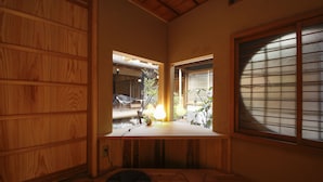 A traditional Japanese room with tatami flooring, a low wooden table, and a window with shoji screens. - Kariya Ryokan Q (Ako)