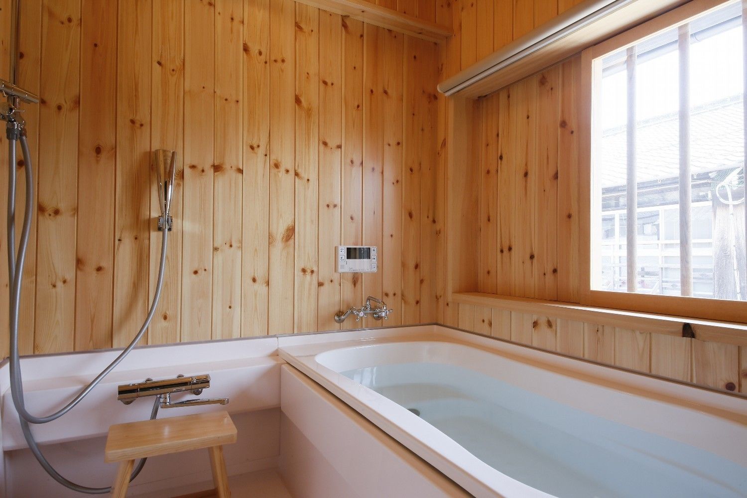 A wooden-paneled bathroom with a bathtub, a shower, and a small wooden stool.