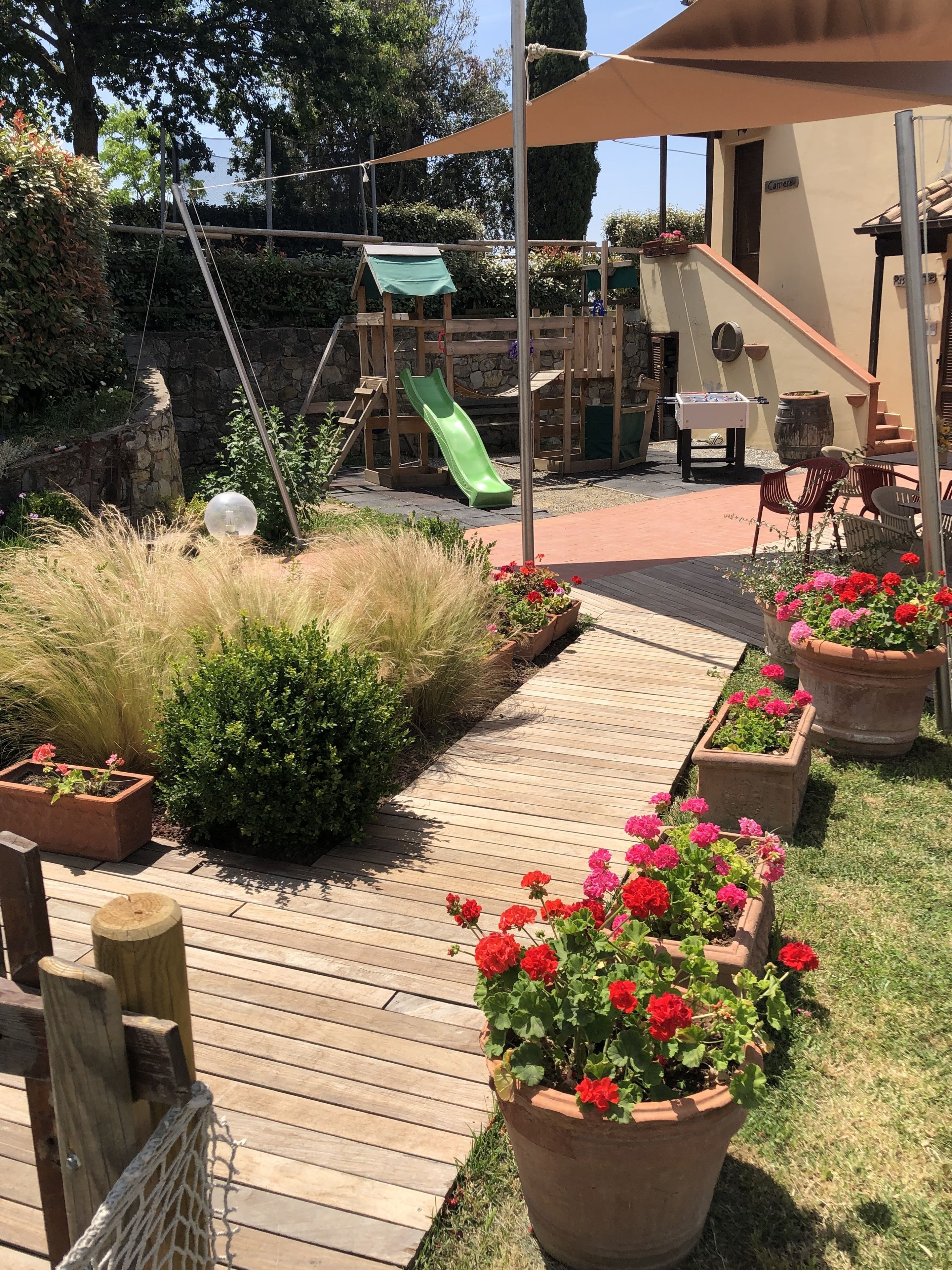 A wooden deck with potted flowers and a slide.