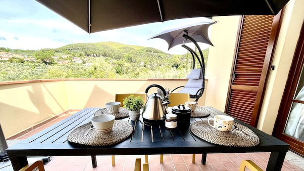 Un balcón con una mesa para dos, que incluye una tetera, tazas y una pequeña planta.