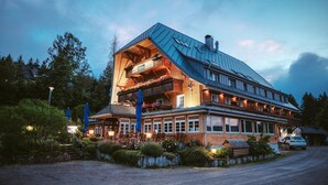 A large building with a sloped roof, multiple windows, and a balcony with flowers. - Hotel Adler Bärental (Feldberg)