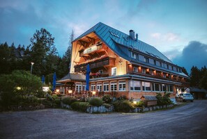 A large building with a sloped roof, multiple windows, and a balcony with flowers. - Hotel Adler Bärental (Feldberg)