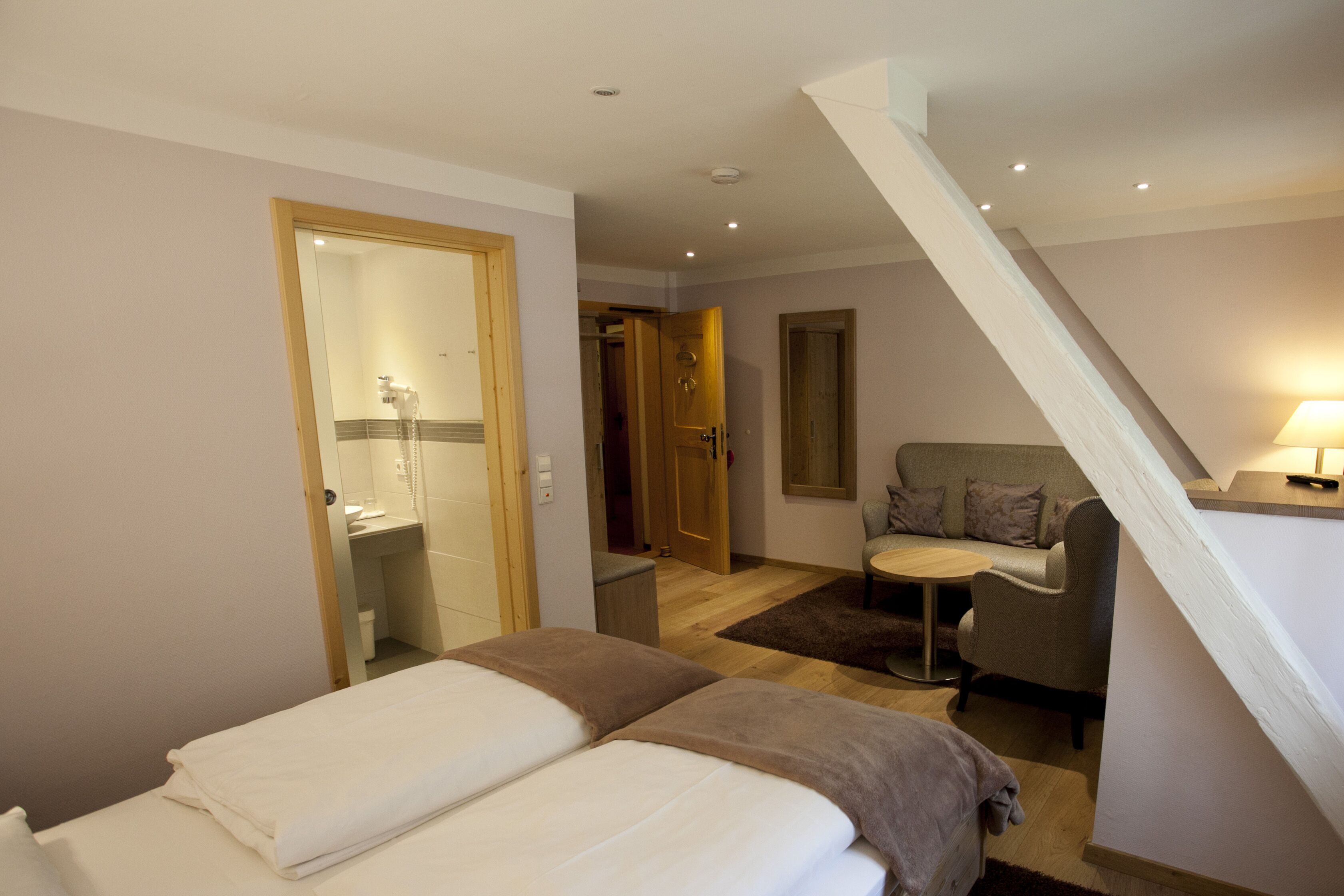 Habitación de hotel con dos camas, un sofá, una mesita y una escalera.