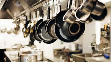 A kitchen with hanging pots and pans, stainless steel countertops, and a sink.