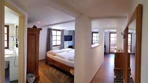 A bedroom with a bed, a TV, a window, and a view of the outside. - Hotel Adler Bärental (Feldberg)