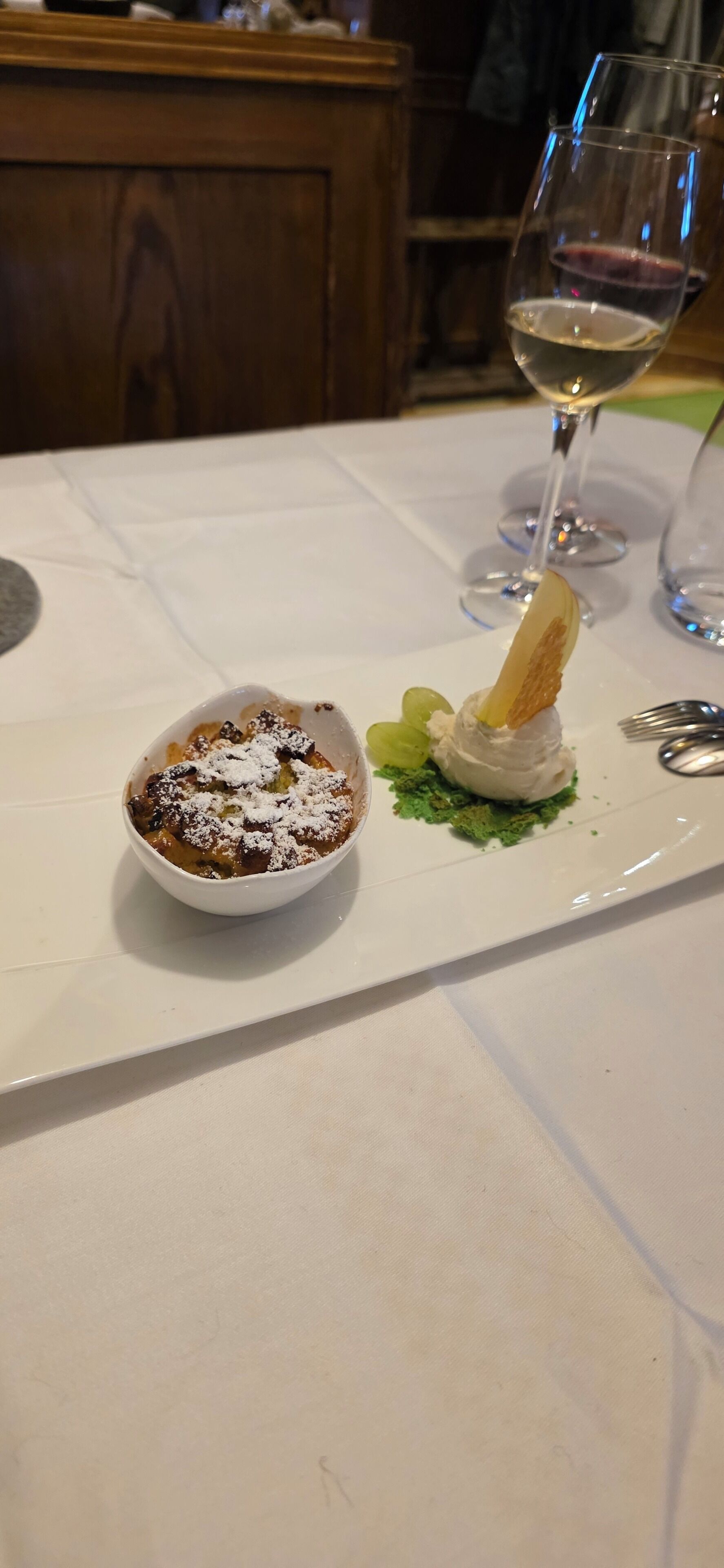A dessert dish on a white tablecloth with a wine glass in the background.
