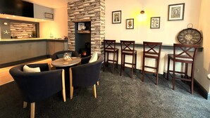 Un comedor acogedor con un muro de piedra decorativo, sillas de madera y una pequeña mesa redonda.