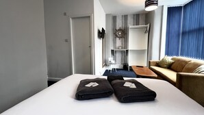 Una habitación de hotel moderna con una cama grande, un sofá, una mesita y un armario.
