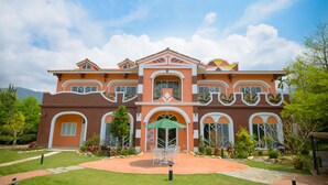 A large, two-story house with a symmetrical facade, multiple windows, and a central entrance with a green umbrella. - Saint Paul Villa (Yuchi)