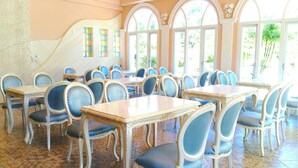 A dining area with multiple tables and chairs, large arched windows, and a patterned floor. - Saint Paul Villa (Yuchi)