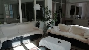 A living room with two sofas, a coffee table, and a large window. - Les Colonnades (Moussan)