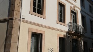 A two-story building with a balcony, large windows, and a small garden area. - Les Colonnades (Moussan)