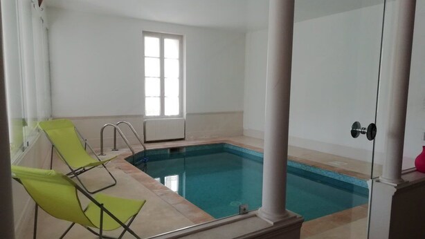 A swimming pool with two green lounge chairs, a window, and a door. - Les Colonnades (Moussan)