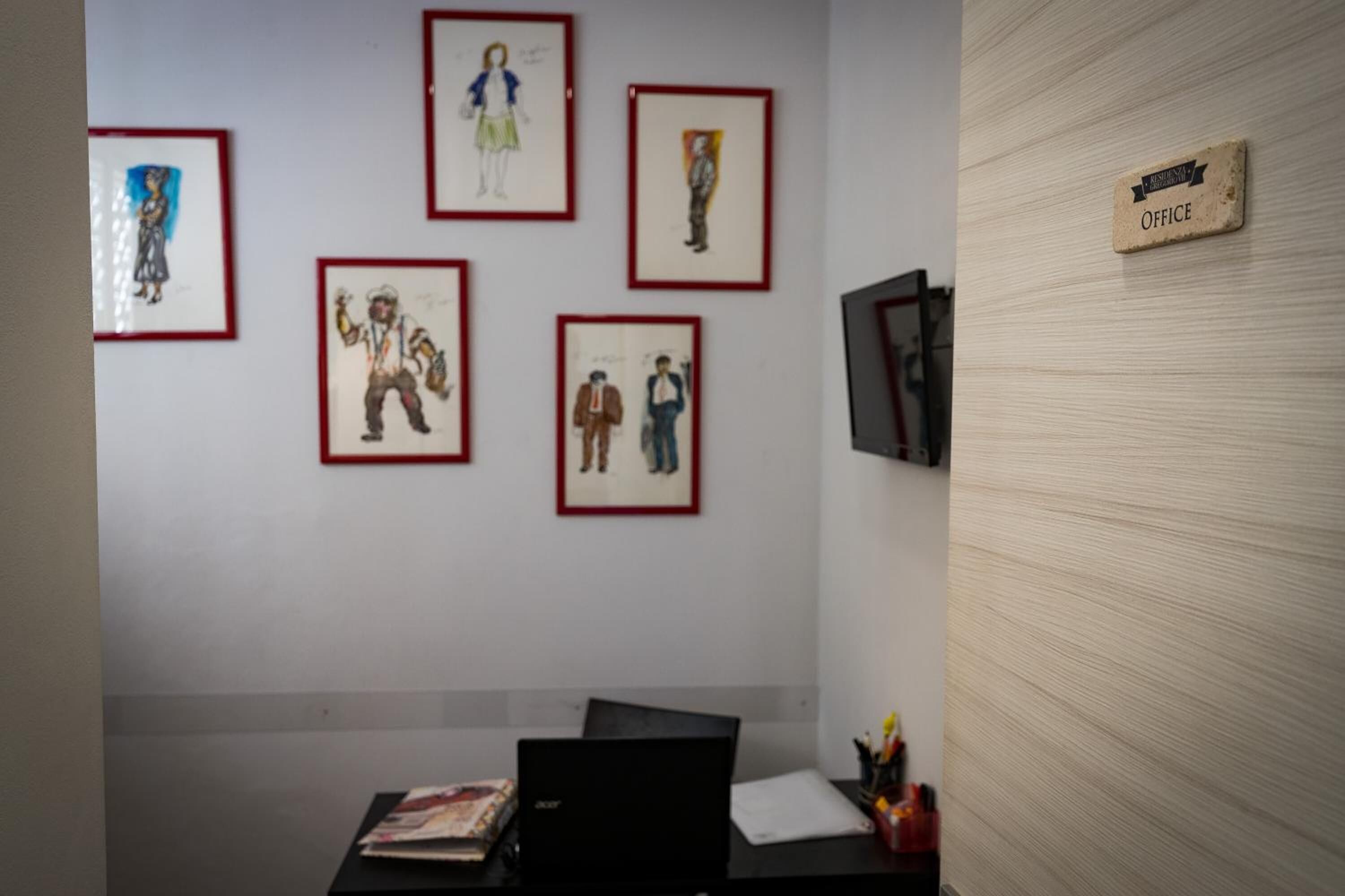 A room with a desk, a laptop, and framed artwork on the wall.