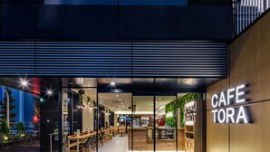 Un café moderne avec une entrée en verre, un intérieur en bois et une enseigne indiquant « CAFÉ TORA ».